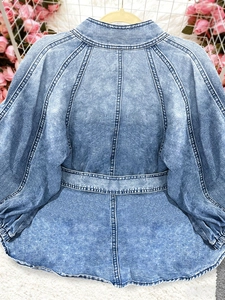 Detailed view of the dark blue washed denim shirt featuring puff sleeves and a cinched waist