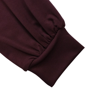 Detailed macro view of the wine red knitted dress featuring elastic ribbed cuffs and soft texture