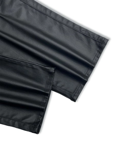Detailed close-up showing the twill texture and stitching of black faux leather trousers