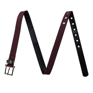 Close-up of burgundy fabric belt with silver square buckle and double rows of metal eyelets