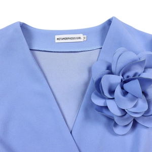 Detail of blue V-neck dress featuring a 3D floral accent and textured crepe fabric