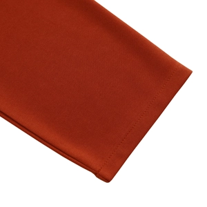 Close-up of the burnt orange knit fabric texture and fine stitching on the dress sleeve