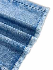 Détail macro du tissu denim bleu clair avec bordure effilochée style décontracté