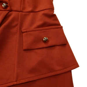 Close-up of burnt orange dress fabric with mesh texture and gold spherical buttons