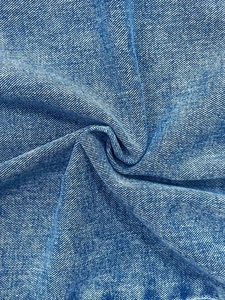 Gros plan du tissu denim bleu clair avec tissage sergé et effet délavé au sable