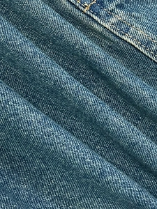 Macro texture of blue denim fabric with twill weave and yellow contrast stitching detail