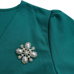 Nahaufnahme einer Vintage-Perlenbrosche mit Strass auf einem dunkelgrünen Abendkleid