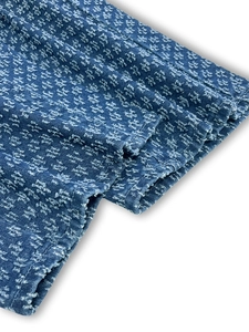 Close-up of deep blue denim fabric with embossed floral patterns and high-quality stitching