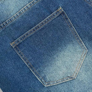 Macro view of blue denim back pocket with yellow contrast stitching and twill texture