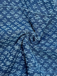 Detailed close-up of blue denim fabric with white floral embroidery and soft drape