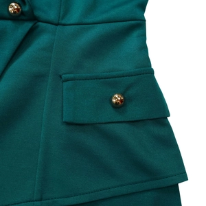 Detailed close-up of dark green ribbed fabric with golden semi-circular buttons and pocket