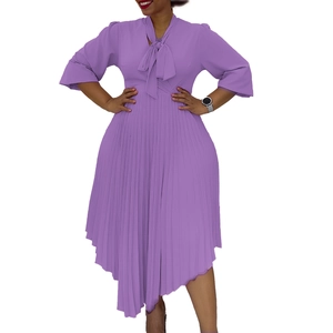 Detail of purple pleated dress featuring pussy-bow neck and asymmetric ruffled hem