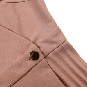 Detailed macro view of gold button and pleated fabric on this pink elegant summer dress