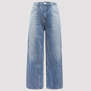 Dettaglio dei jeans a vita alta con decorazioni di perle bianche su denim lavaggio medio