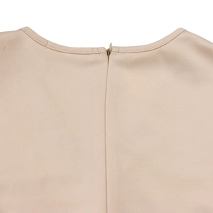 Detail of the invisible zipper and textured fabric on the back neckline of the beige dress