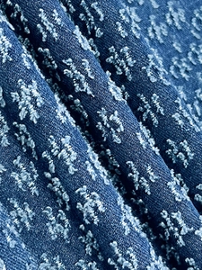 Macro detail of dark blue denim fabric with 3D tufted star pattern and rich texture