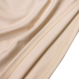 Close-up of beige knit fabric showing high-quality overlock stitching and fine texture