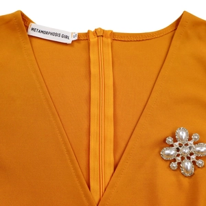 Detailaufnahme des V-Ausschnitts mit Perlenbrosche und verdecktem Reißverschluss am Kleid