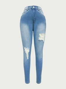 Détail du jean skinny bleu clair avec déchirures aux genoux et bords effilochés blancs usés