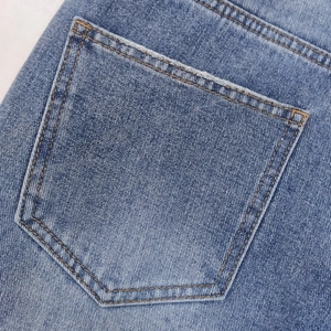 Dettaglio della tasca in denim blu con borchie metalliche e cuciture a contrasto