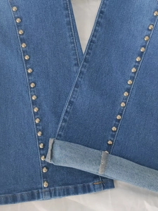 Detail view of silver metal rivets on blue flared jeans with high-quality twill denim texture