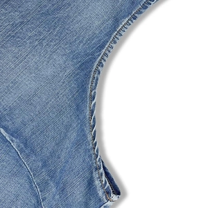 Detail of light blue washed denim dress showing double-stitched seams and twill fabric