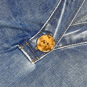Macro view of blue denim fabric with contrast stitching and textured brown button