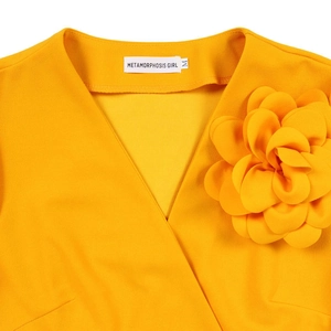 Detail of a bright yellow V-neck dress featuring a large 3D fabric flower and crepe texture