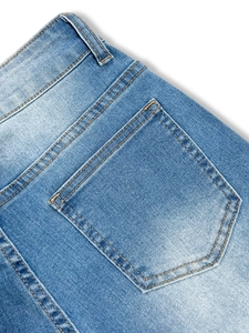 Détail de la poche arrière d'un jean délavé clair avec doubles coutures dorées