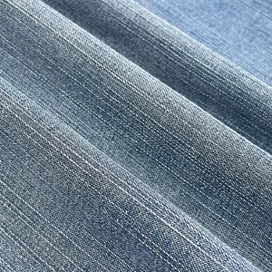 Detailed close-up of light blue washed denim fabric with vertical white pinstripe patterns