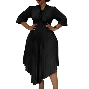 Detail of elegant black pleated dress featuring a V-neckline with a stylish bow tie