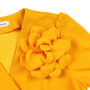 Detailed view of the V-neck with a large 3D floral decoration on the pleated yellow dress