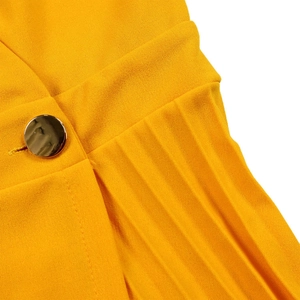 Detail of elegant pleated yellow dress fabric featuring a round gold metal button