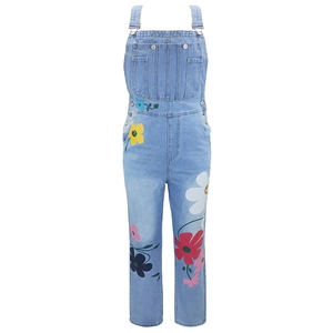 Detail of light blue denim overalls featuring vibrant floral prints and metal buckles