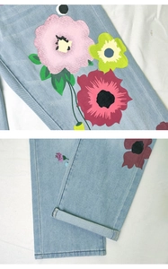 Detail of light blue straight denim jeans with colorful artistic floral patterns