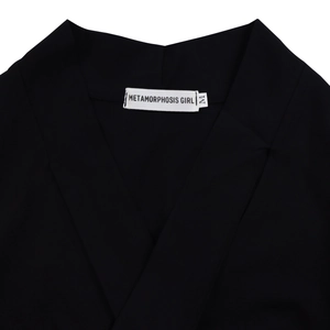 Detail of elegant black pleated dress showing V-neckline and inner brand label