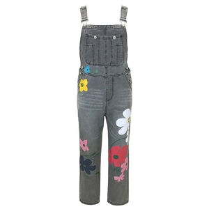 Detail of gray denim overalls with vibrant floral prints and metal adjustable buckles