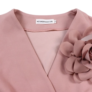 Detailed view of the V-neck with a large decorative fabric flower on the pink dress