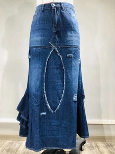 Dettaglio della gonna in denim con orlo a balze asimmetrico e design patchwork usurato