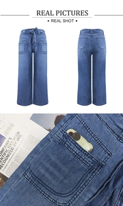 Detail of high-waisted wide-leg jeans featuring a waist tie bow and large front patch pockets