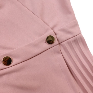 Detailed view of pink V-neck dress with golden buttons and elegant pleated design