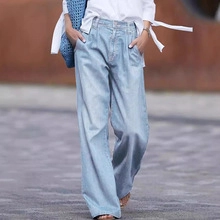 Detail of high-waist wide-leg light blue denim trousers with front pleats for women