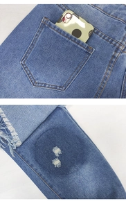 Detail of blue denim jeans featuring distressed frayed edges and rear pocket stitching