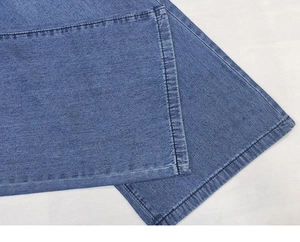 Detailed close-up showing the hem stitching and texture of blue denim wide-leg jeans