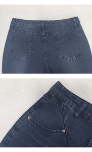 Detail view of dark blue denim jeans with copper rivets and neat stitching accents