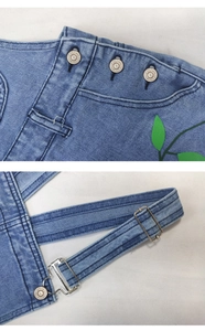 Détails de robe en jean bleu clair avec imprimé feuilles et boutons métalliques