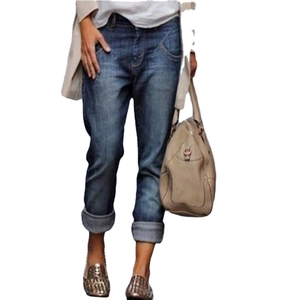 Woman in casual dark blue straight-leg jeans with beige cardigan and handbag outfit