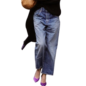 Mid-blue wash straight-leg denim jeans styled with purple heels and a woven handbag