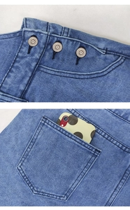 Détail de trois boutons métalliques et poche arrière sur short en jean bleu avec vue portable