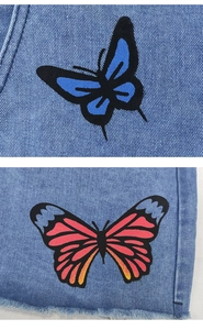Détail du tissu denim avec imprimés papillons colorés et bords effilochés stylés
